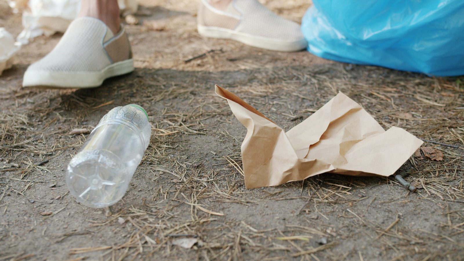 Plastic bottle and crumpled paper on ground